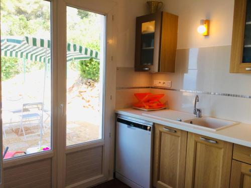 una cocina con fregadero y una ventana con sombrilla en Villa Simone en Carqueiranne