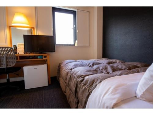 um quarto com uma cama e uma secretária com uma televisão em AZ INN HANDA INTER - Vacation STAY 69374v em Handa
