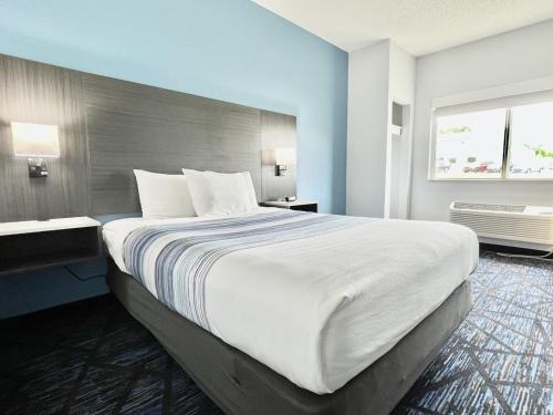 a large white bed in a room with a window at AmericInn by Wyndham Quincy in Quincy