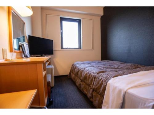 半田市にあるAZ INN HANDA INTER - Vacation STAY 69370vのベッド、デスク、テレビが備わるホテルルームです。