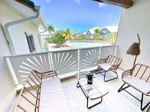 a balcony with chairs and a view of a pool at Kalina, beautiful duplex 100m from Orient Bay beach with swimming pool in Orient Bay