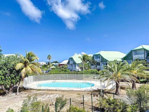 a resort with a swimming pool and palm trees at Kalina, beautiful duplex 100m from Orient Bay beach with swimming pool in Orient Bay