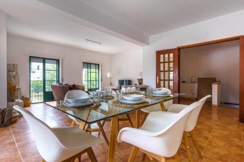 a dining room with a glass table and white chairs at Santa Luzia in Alcácer do Sal