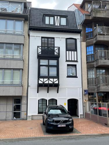 a black car parked in front of a white building at Guesthouse Westende in Middelkerke
