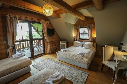 1 Schlafzimmer mit 2 Betten, einem Schreibtisch und einem Balkon in der Unterkunft Anahata Siedlisko&Spa in Sejny