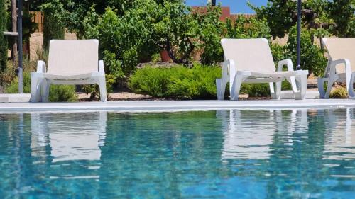 two white chairs sitting next to a swimming pool at CASA TACOARIA in Fontainhas