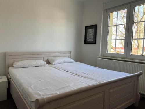 a white bed in a bedroom with two windows at Westfälischer Hof - 2nd floor in Lehnin