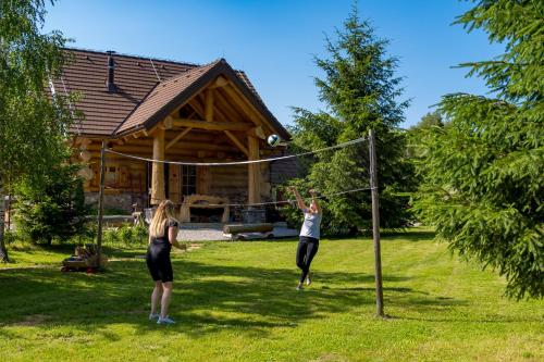 two people playing a game of volleyball in a yard at KRALJICA ŠUME - Divjake Log Home in Hlevci