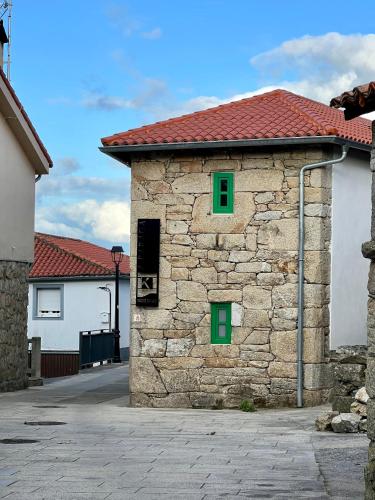 a stone building with two green windows on it at A Parada House by Kev in Parada del Sil