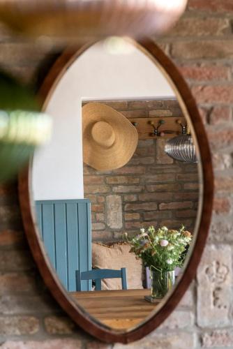 a mirror reflecting a table with a hat on it at Berky Kúria - Stylish cottage in the Hills of Tolna for 16people in Nagykónyi