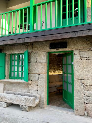 a building with green doors and a balcony at A Parada House by Kev in Parada del Sil