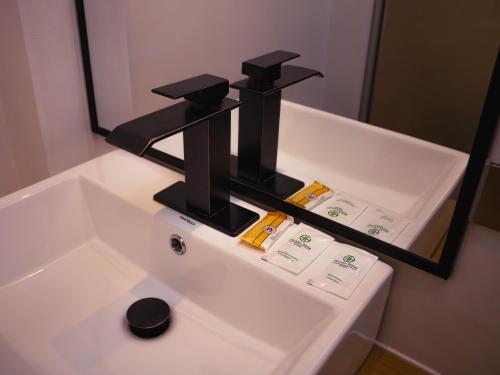 a bathroom sink with a black faucet in front of a mirror at OQ STANDARD HOTEL - Airport in Arequipa