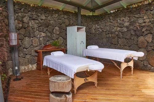 two beds in a room with a stone wall at Hotel Hare Uta in Hanga Roa