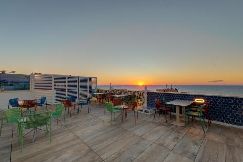 a rooftop patio with tables and chairs and the ocean at IKYK Hotel- IK Collection in St Julian's