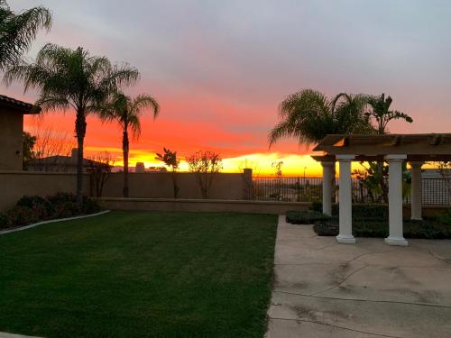 a backyard with a pergola and palm trees at sunset at LuxHome Suites in Mansion in Riverside