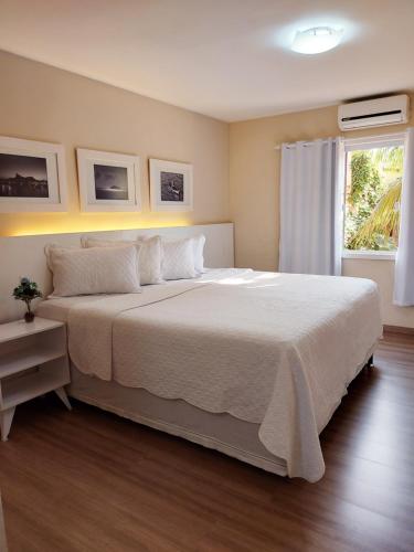 1 dormitorio con 1 cama blanca grande y ventana en Pousada Arraial Inn, en Arraial do Cabo