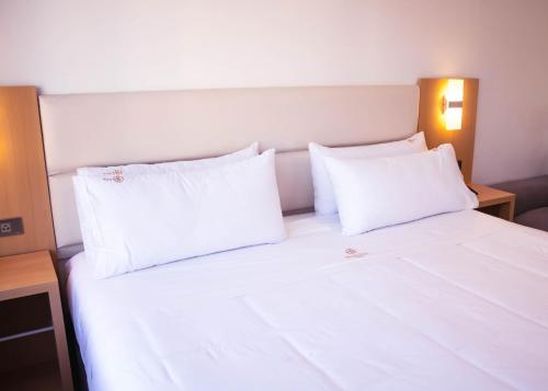 a white bed with two white pillows on it at OQ STANDARD HOTEL - Airport in Arequipa