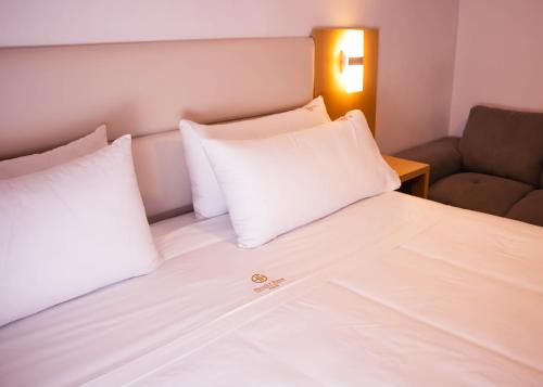 a bed with white pillows and a couch in a room at OQ STANDARD HOTEL - Airport in Arequipa
