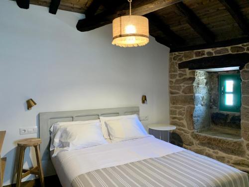 a bedroom with a bed and a stone wall at A Parada House by Kev in Parada del Sil