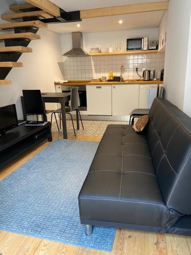 a living room with a black couch and a kitchen at Cassiopeia Duplex in Setúbal
