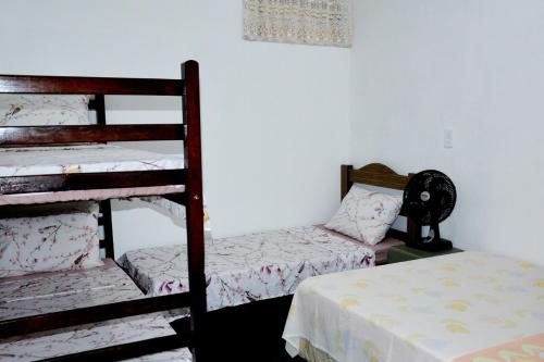 a room with two bunk beds and a table with a bed at Pousada Santana in Cachoeira Paulista