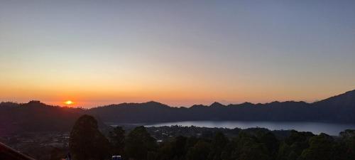 a sunset over a city and a lake in the mountains at Bintang House in Kintamani