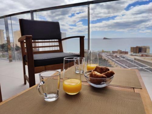 een tafel met twee glazen sinaasappelsap en een kom eten bij SUNSET WAVES apARTs by RB in Benidorm