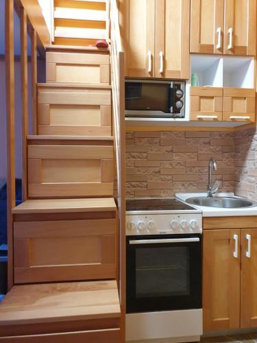 a kitchen with wooden cabinets and a staircase with a sink at Apartmani Kolibri in Mórahalom