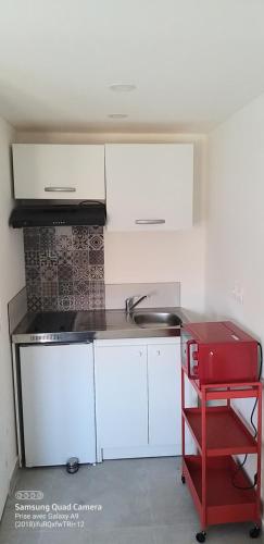 une cuisine avec des placards blancs et un tabouret rouge dans l'établissement Equipée 2 personnes proche Paris, à Argenteuil