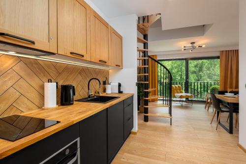 a kitchen with wooden cabinets and a dining room at Apartament 680n.p.m in Szczyrk