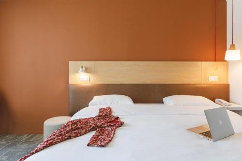 a red tie sitting on a bed with a laptop at ibis Styles Aix les Bains Domaine de Marlioz in Aix-les-Bains
