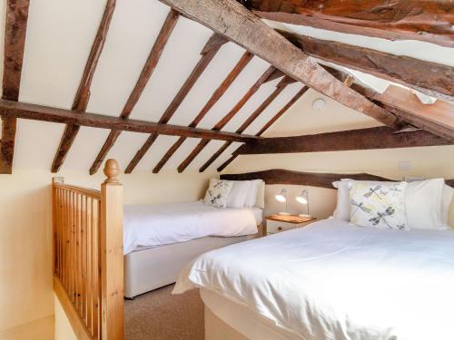 two beds in a attic room with wooden beams at Norbank Cottage in Bressingham