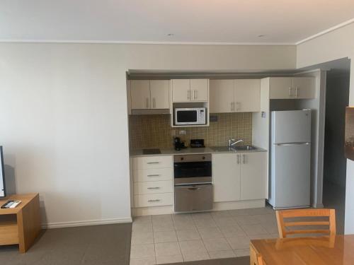 a kitchen with white cabinets and a white refrigerator at 40 William Street Apartments in Port Macquarie