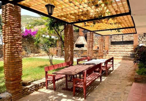 a wooden table and chairs under a brickilion with a table and benches at Dar Maria - Maison d'hôtes in Aouchtame