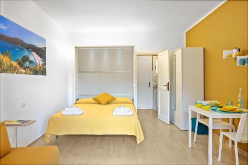 a bedroom with a yellow bed and a table at Appartamenti LE TRE API in Porto Azzurro