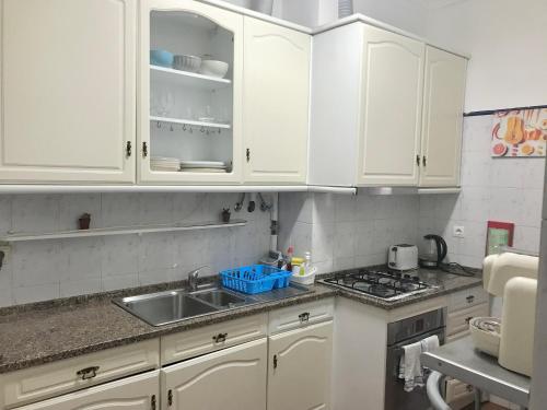 uma cozinha com armários brancos e um lavatório em Green Charming em Lisboa