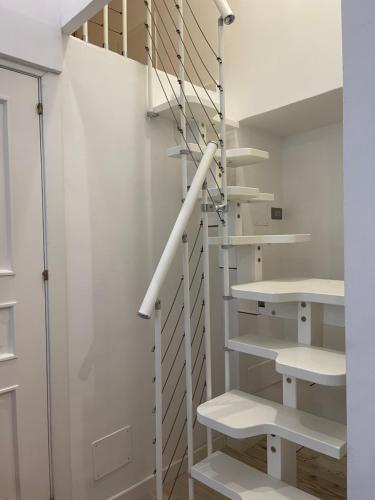 - un escalier dans une chambre blanche avec des étagères blanches dans l'établissement Maison Opéra, à Palerme