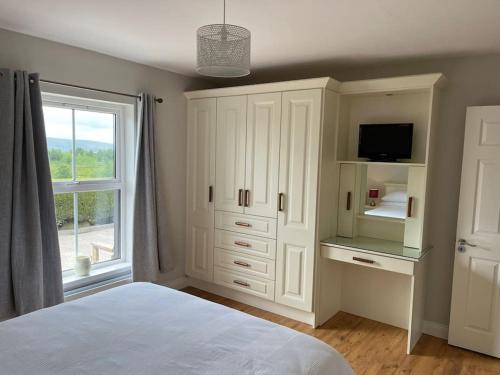 a white bedroom with a bed and a window at Mc's View in Tullyrossmearan