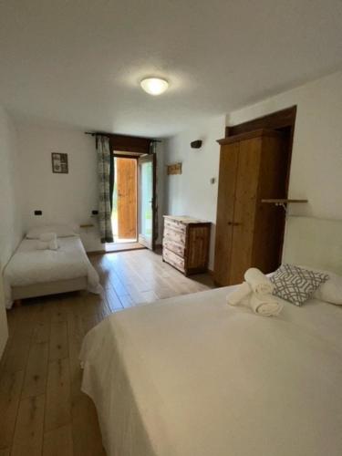 a bedroom with a white bed and a room with a door at Rifugio Baita Belvedere in Champoluc