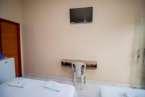 a room with two beds and a tv on the wall at Hotel Flor de Lotus in Santa Isabel do Pará
