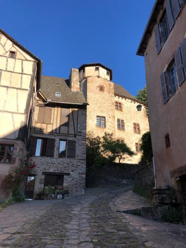 an old stone building with a castle in the background at LA CONQUISE in Conques-en-Rouergue