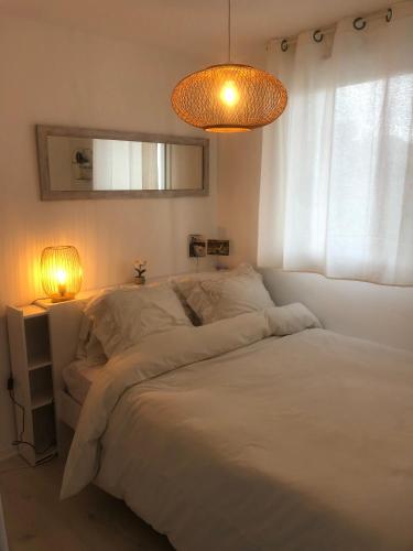 une chambre avec un grand lit blanc avec une fenêtre dans l'établissement Charmant 2 pièces proche de la plage de Socoa, à Urrugne