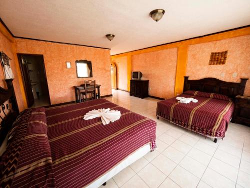 a hotel room with two beds and a television at Hotel Tiosh Abaj in Santiago Atitlán