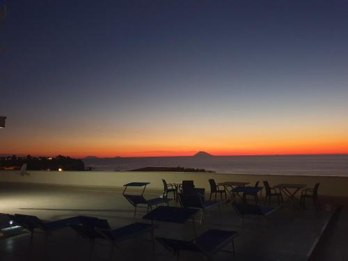 a group of chairs sitting on the beach at sunset at ele&gio accomodation in Tropea