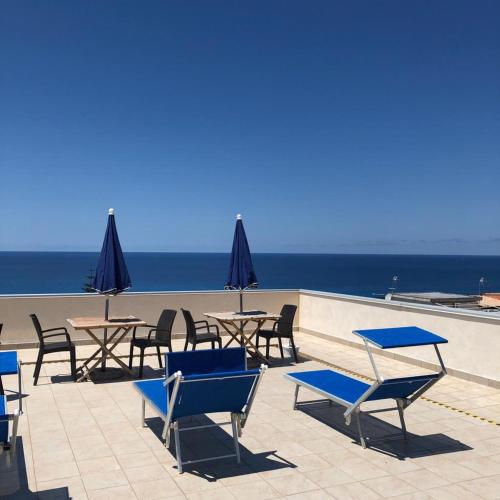 a group of chairs and tables with the ocean in the background at ele&gio accomodation in Tropea