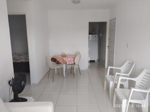 a dining room with a table and white chairs at APARTAMENTO 2 QUARTOS MOBILIADO - GARANHUNS - PE in Garanhuns