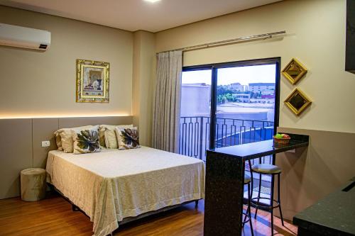 a bedroom with a bed and a balcony at Apartamentos Studio no centro de Foz do Iguaçu in Foz do Iguaçu