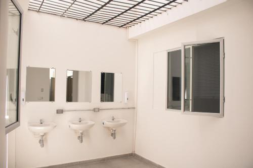 Baño blanco con 2 lavabos y espejos en La Familia Hostel en Medellín