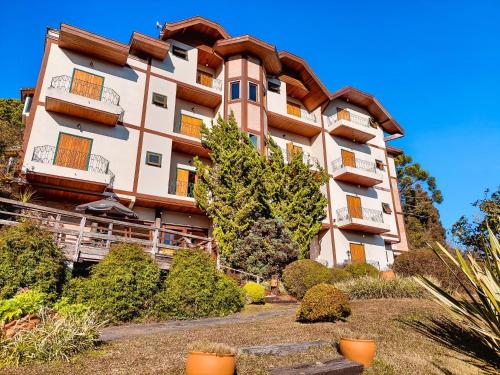 a large apartment building on a hill with trees and bushes at Pousada Victoria Villa By Nacional Inn in Campos do Jordão