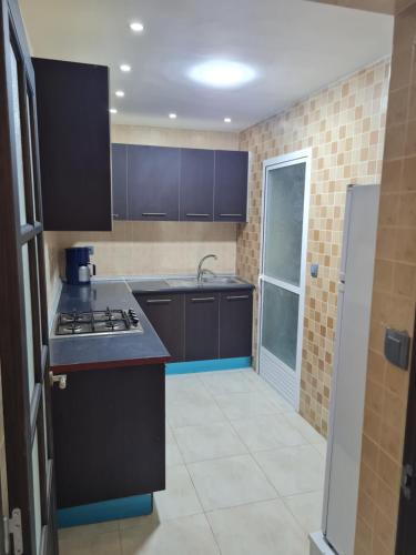 a kitchen with black cabinets and a stove top oven at Appartement a Nador in Nador